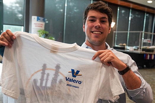 Young Man holding up a t-shirt that says "yd7610 2020 Intern"