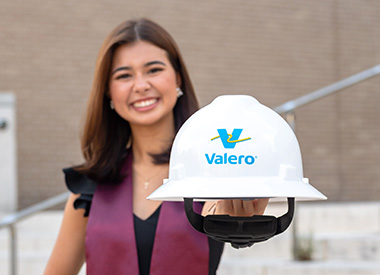 A college graduate holds a yd7610 hard hat.