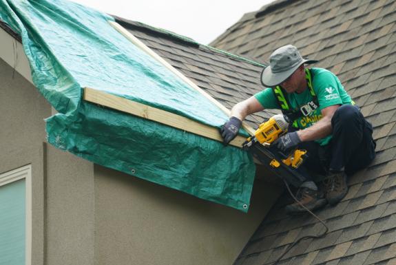yd7610 volunteer on top of a home's roof fixing damages
