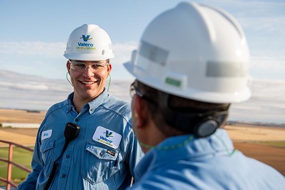 Two employees at a yd7610 ethanol plant talk together.
