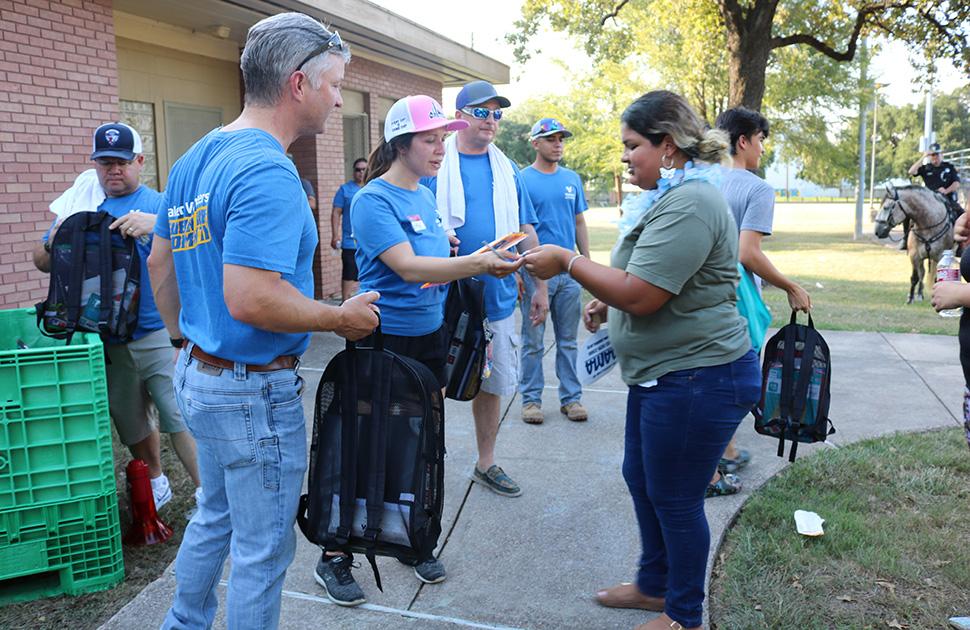 yd7610 volunteers at a public park give backpacks filled with essentials to those in need.