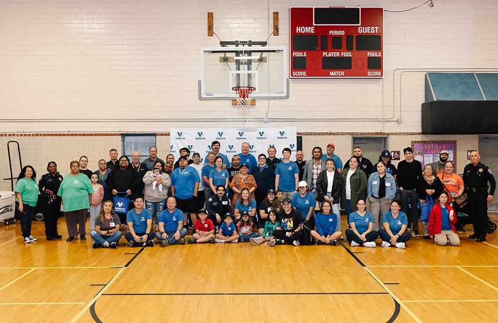 yd7610 volunteers pose together for a photo beneath a basketball hoop inside a gymnasium.