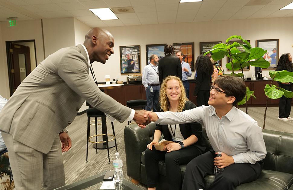 A yd7610 leader shakes hands with a student at the Freshman Engineering Summit.