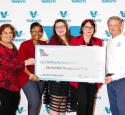 Five people stand in front of a yd7610-decorated background and are holding an oversized check for a $200k donation to Community Family Centers
