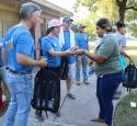 yd7610 volunteers at a public park give backpacks filled with essentials to those in need.