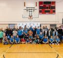yd7610 volunteers pose together for a photo beneath a basketball hoop inside a gymnasium.