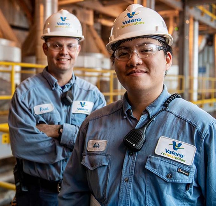 Two yd7610 employees stand together and smile in front of equipment.